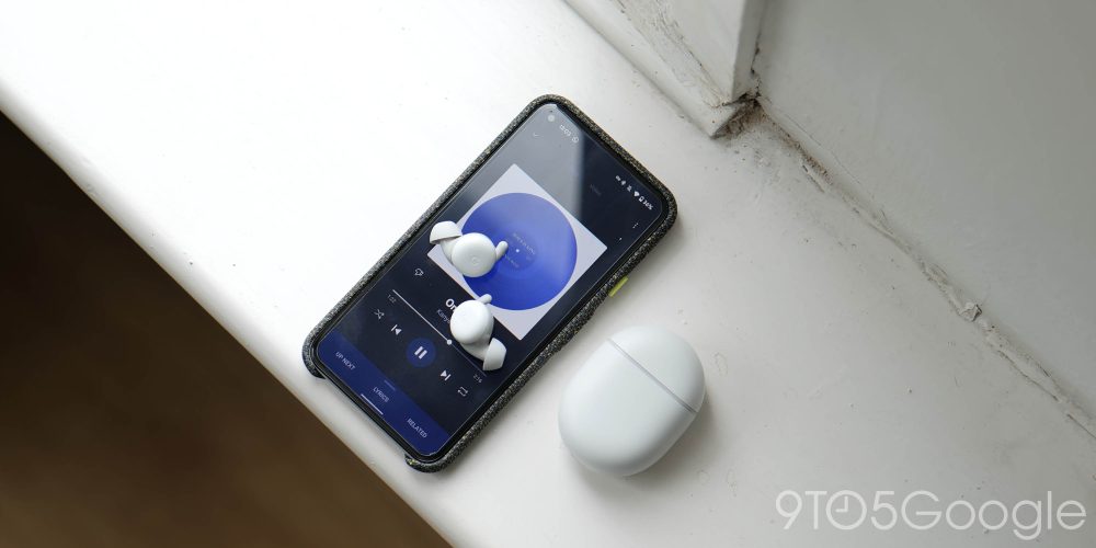 Pixel Buds A-series earbuds placed upon the display of a Pixel 5 running YouTube Music that is playing Kanye West "On God".