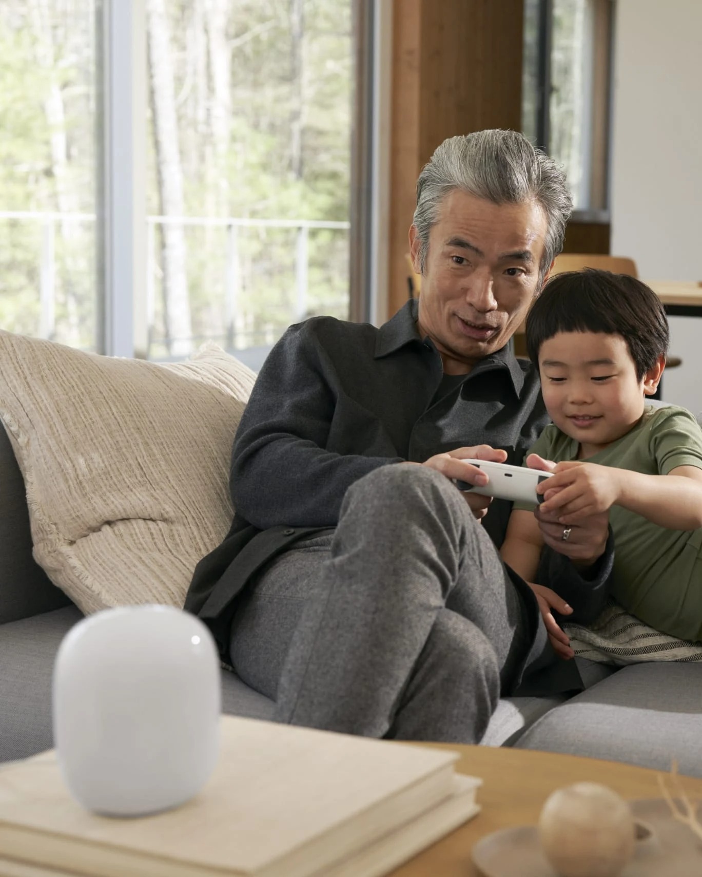 A man and a child playing a game on Stadia together, with the Nest Wifi Pro in the foreground